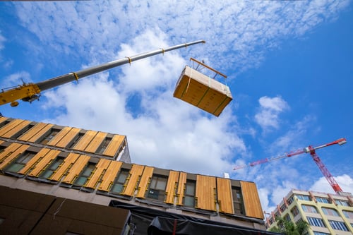 Crane moving modular construction parts onto a building.