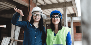 two women wearing hardhats on a construction site