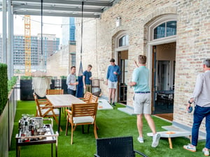 Men playing cornhole on a bar patio