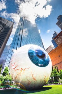 tall skyscraper behind giant eyeball statue