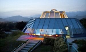 a house made to look like a round spaceship against light blue mountains