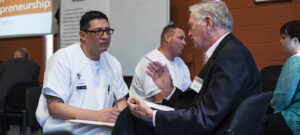 Representative of non-profit organization Prison Entrepreneurship Program speaking with an inmate