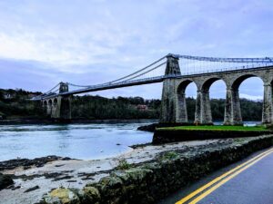 The Menai Bridge constructed of limestone and 16 chain cables spans 577-feet long connecting the island of Anglesey and mainland Wales