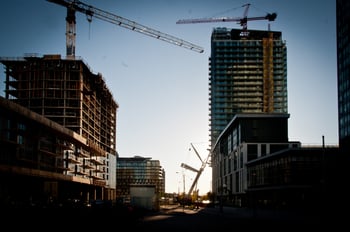 Multiple construction sites and cranes in a city at dusk.