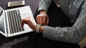 man working on a laptop checking his watch