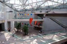 a lobby with big skylights and colorful flags going across the ceiling