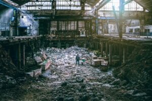 man standing in cluttered and destroyed factory