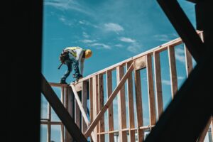 man on top of a wooden house frame