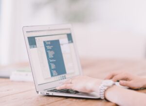 a pair of hands typing on a laptop