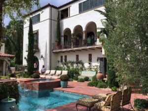 Spanish style mansion overlooking a brick courtyard leading to a blue pool