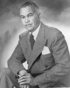 black and white picture of a mustached man in a suit, architect Paul R Williams
