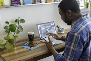 Man sitting at his desk on his phone with laptop opened. 