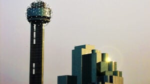 a tall skyscraper with an orb at the top against an evening sky