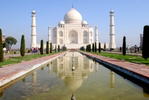 a walkway of water leading to a beautiful white palace, the Taj Mahal in India