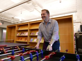 Beck Technology team member happily playing foosball in the Beck Technology office. 