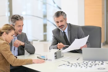 Three people at a conference table discussing work