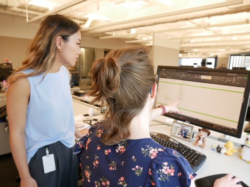 Two Beck Technology employees discuss information displayed on a computer screen. 