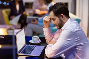 Thoughtful businessman working on laptop in office at night