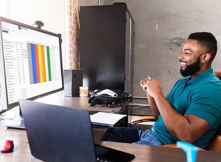 Smiling man at his desk looking at a screen with Bid Day bid leveling software.